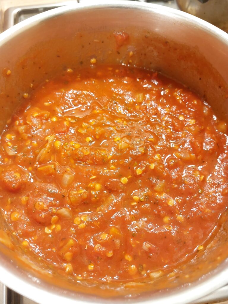 A close up of tomato sauce cooking in a silver pot.