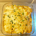 Creamy tuna bake straight from the oven, topped with chopped green onions, in a square glass form.