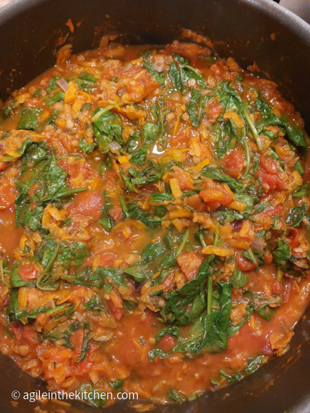 Healthy tomato sauce in a pot. Spinach, shredded carrots and red lentils are all visible.