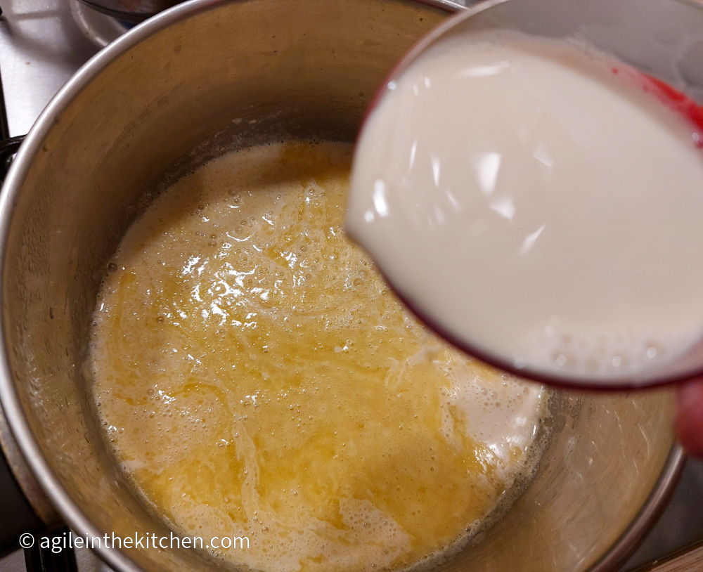 Basic roux cooking on the stove, while adding milk to create the mac n' cheese sauce.