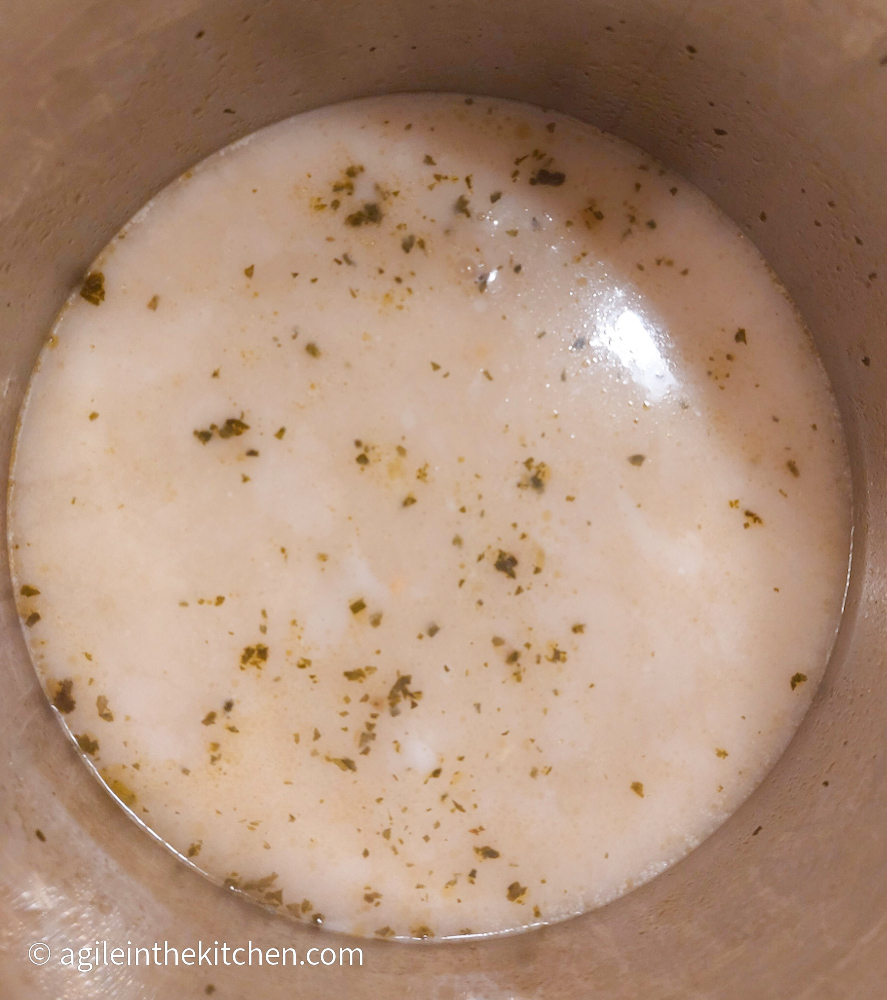 Coconut milk and vegetable stock cooking together in a silver pot to make Coconut Ramen