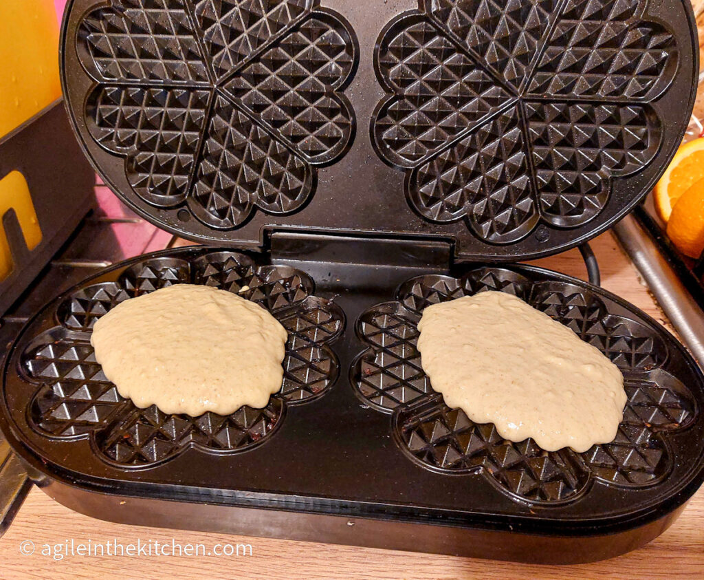 Waffle batter poured into a waffle maker to make two waffles