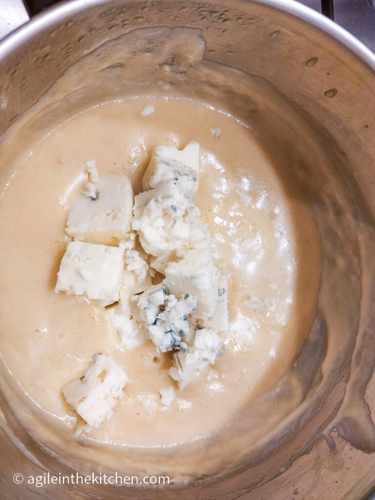 Blue cheese added into a pot of creamy bechamel sauce, to make tangy blue Mac n' Cheese