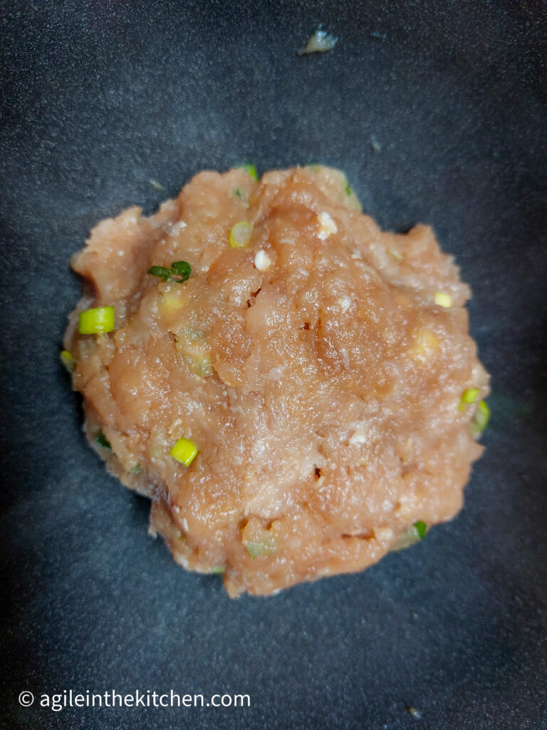 On a black background, Asian hamburger mince mixed together in to one clump