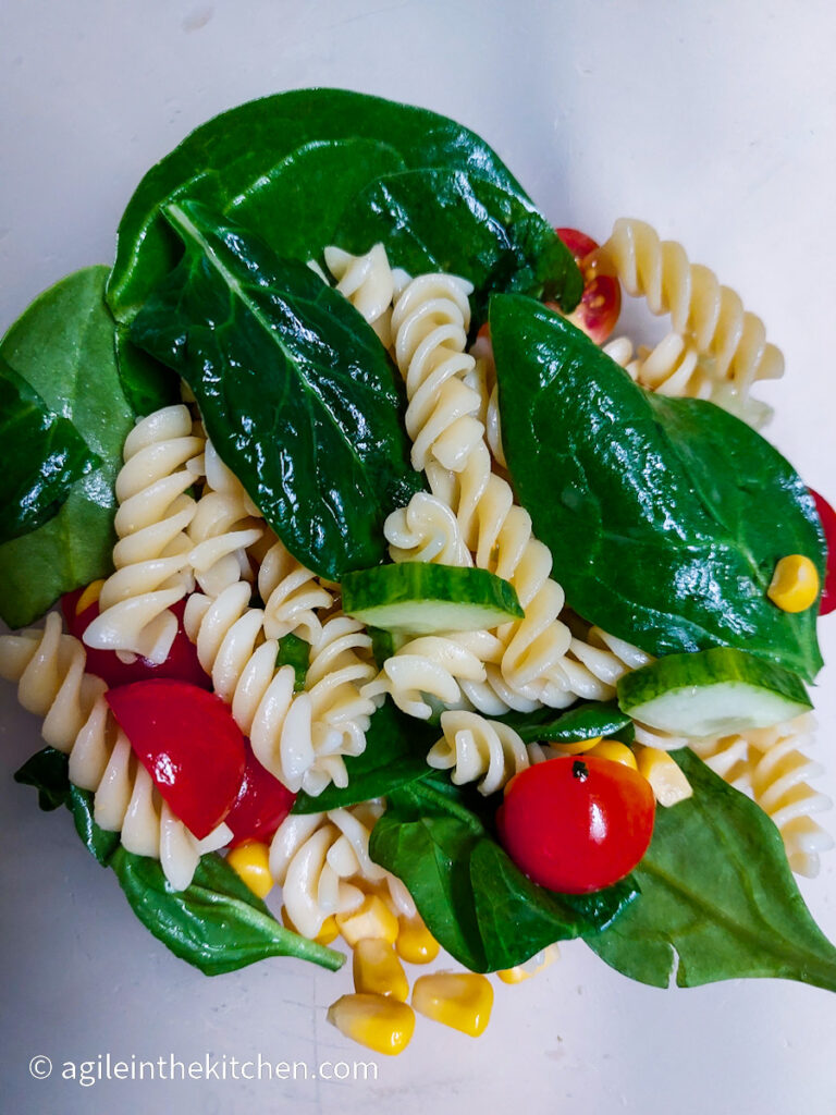 Mixed pasta salad, with spinach, fusili pasta, grape vine tomatoes cut in half, corn from a can