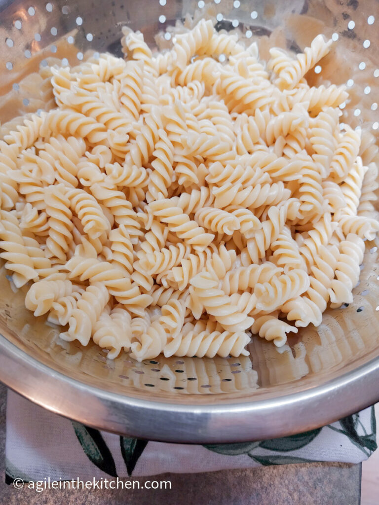 In a silver colander, cooked fusili pasta