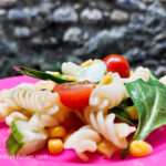 On a pink plate, a close up of a basic pasta salad