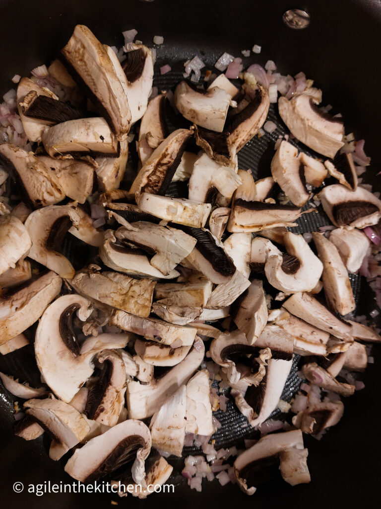 In a pot, sliced mushrooms cooking down.