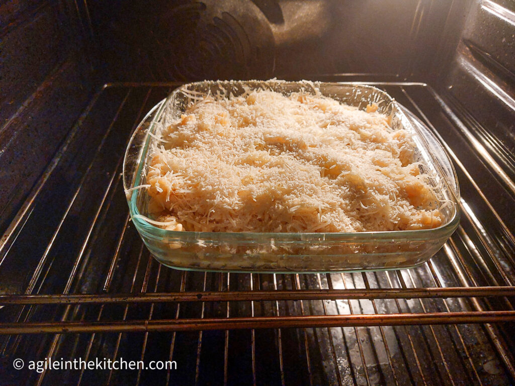 A photo taken from inside the oven where there is a glass pan with mac n cheese, with a panko breadcrumb ready to be baked.