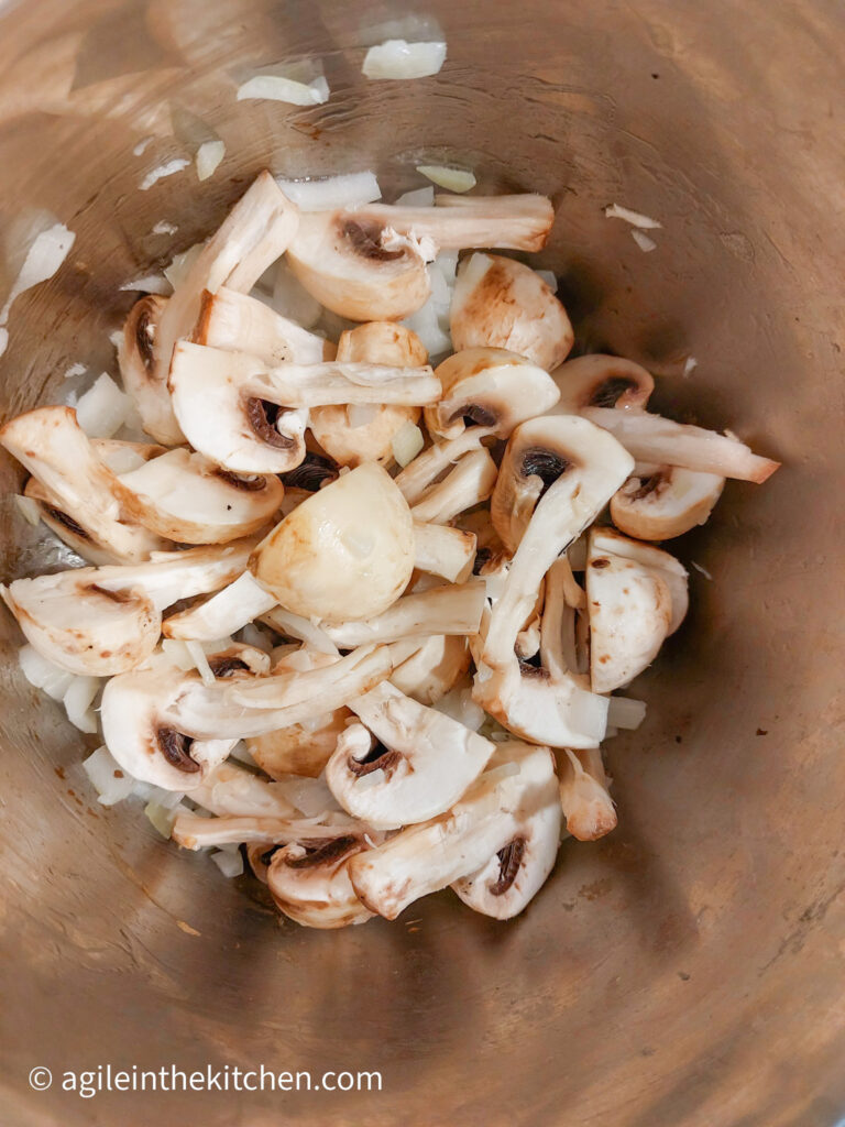 In a pot, mushroom and onion are being cooked together