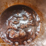 A pot filled with Teriyaki sauce that is cooking, forming bubbles on the surface.