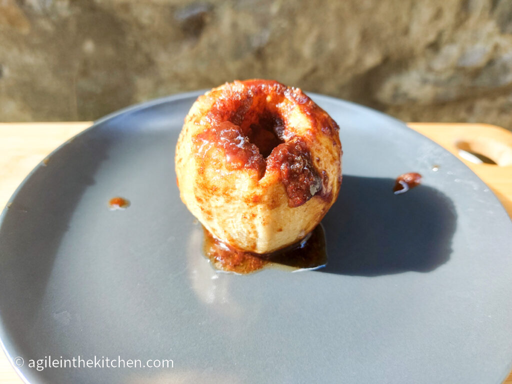 On a grey plate, a baked apple with a cinnamon mixture.