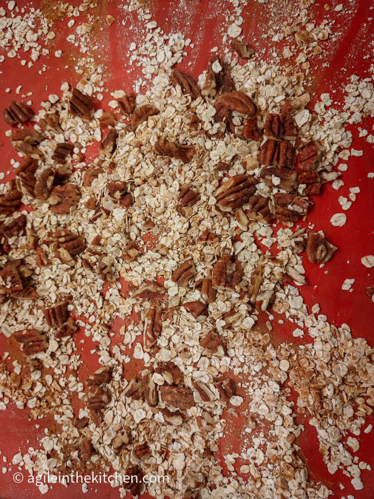 On a red silicone sheet, oats, cinnamon and chopped pecans mixed.