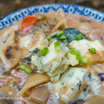 A close up of a photo taken from above, a blue patterned ceramic bowl filled with bluecheese pasta topped with green onions
