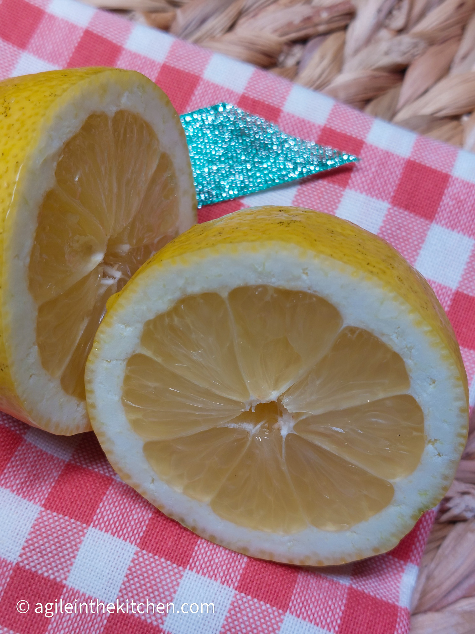 A close up of a sliced lemon on top of a red gingham cloth.